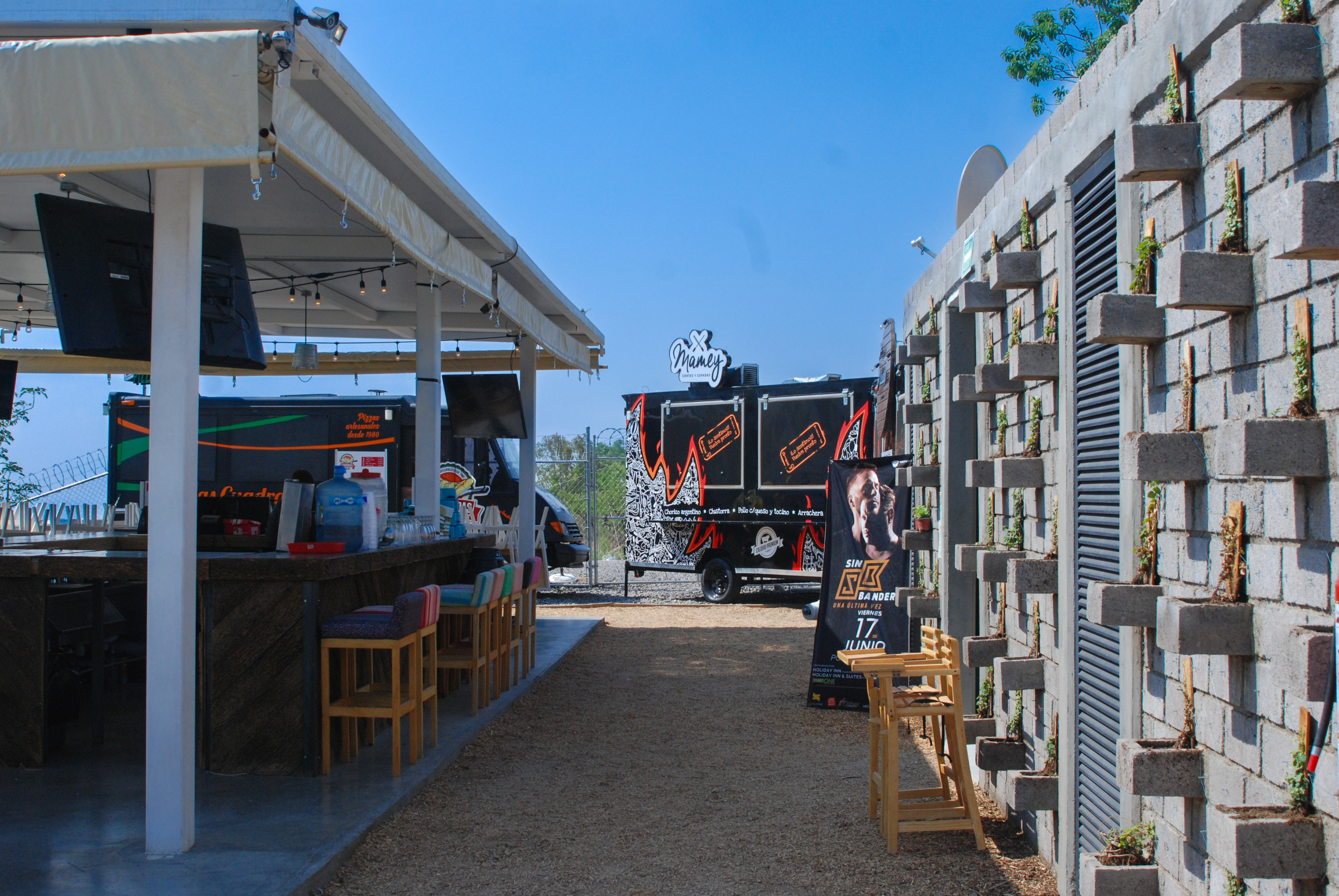 Área de comensales con sombreaderos tensados y camiones de comida, construcción comercial Fer Et Ciment Guanajuato